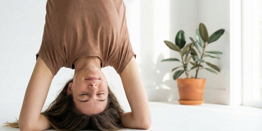 Mujer en sirsasana, inversión sobre cabeza simbolizando elevación espiritual del chakra corona