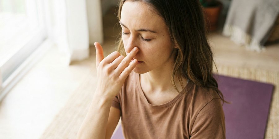 Mujer practicando pranayama con técnica de respiración alternada nasal